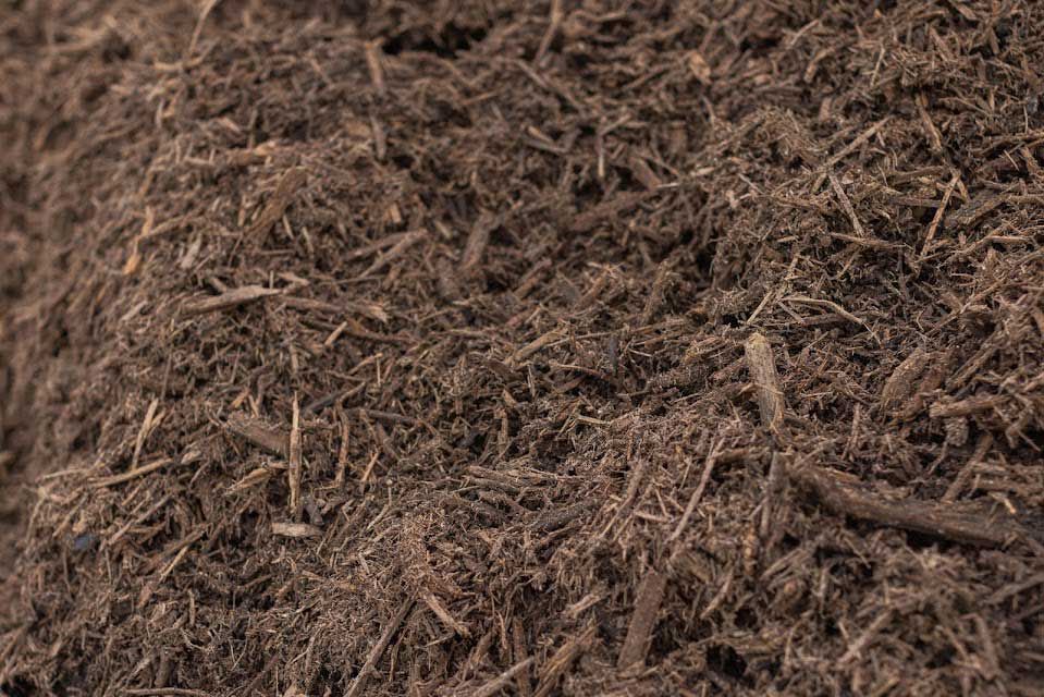 Brown mulch, shredded wood, covering ground, used for gardening or landscaping.
