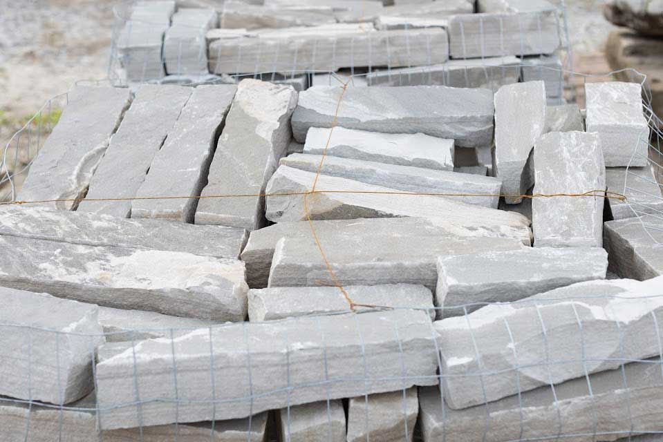 Pile of gray rectangular stones wrapped in wire mesh.
