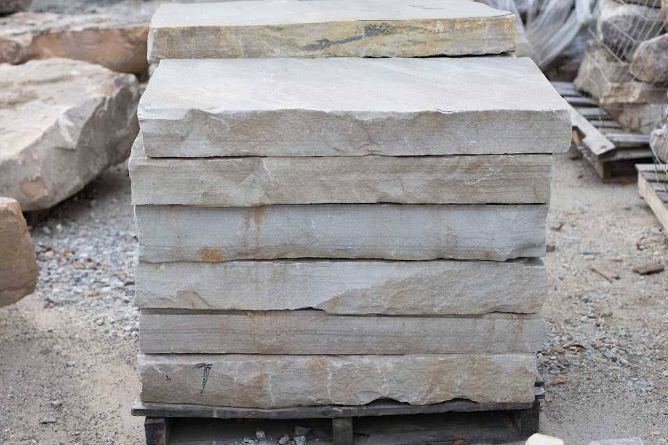 Stack of light gray rectangular stone steps on a wooden pallet.