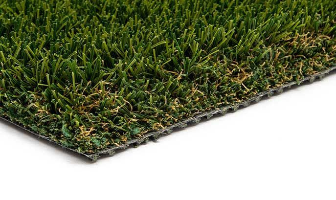 Close-up of artificial turf with green and brown blades against a black backing, on a white background.