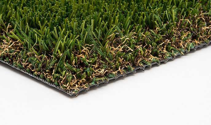 Close-up of artificial turf with green and brown blades against a white background.