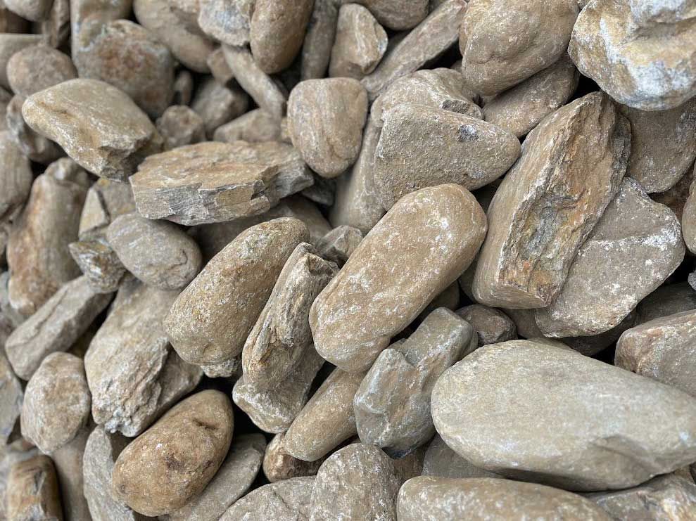 Pile of tan-colored river rocks, varying in size and shape.