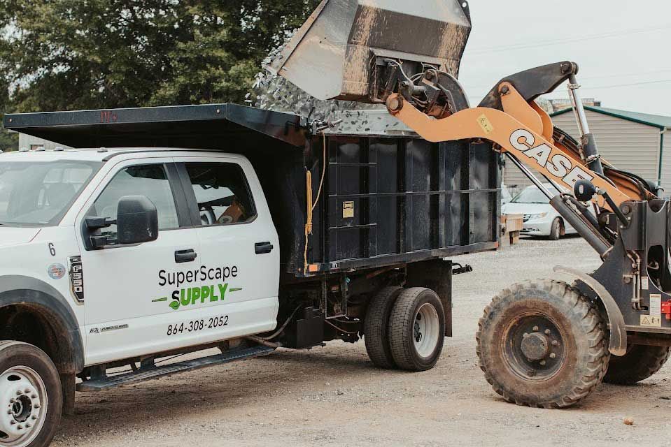 Loader dumping gravel into a dump truck. The truck is white with