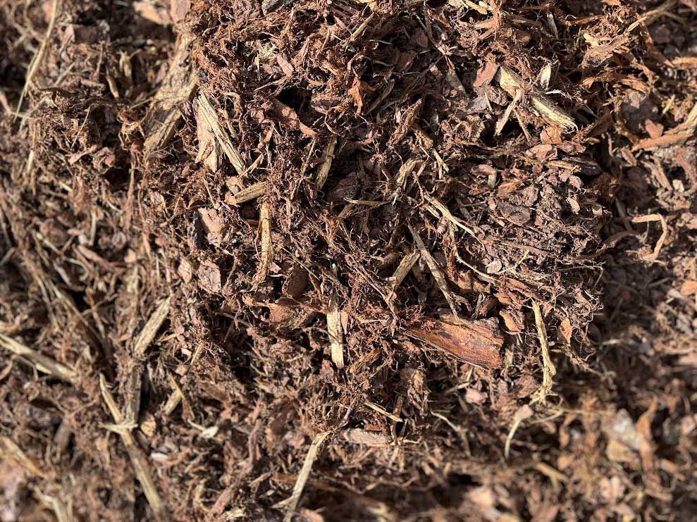 Close-up of dark brown mulch with various sized wood chips and fibers.