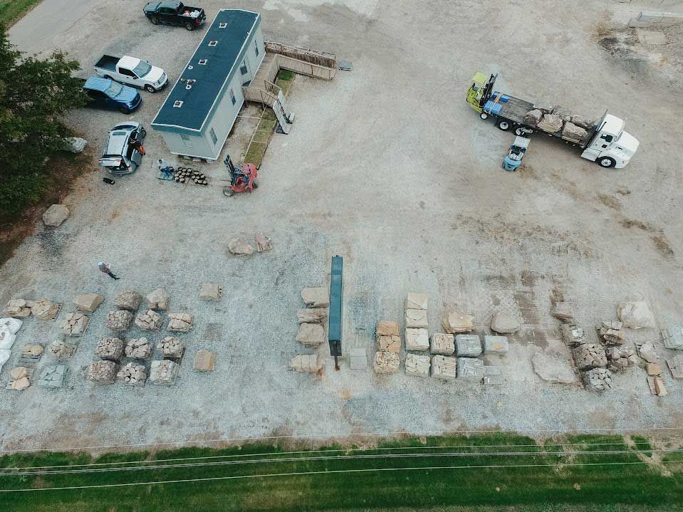 Aerial view of construction site with various blocks and vehicles, including a semi-truck and a small loader.