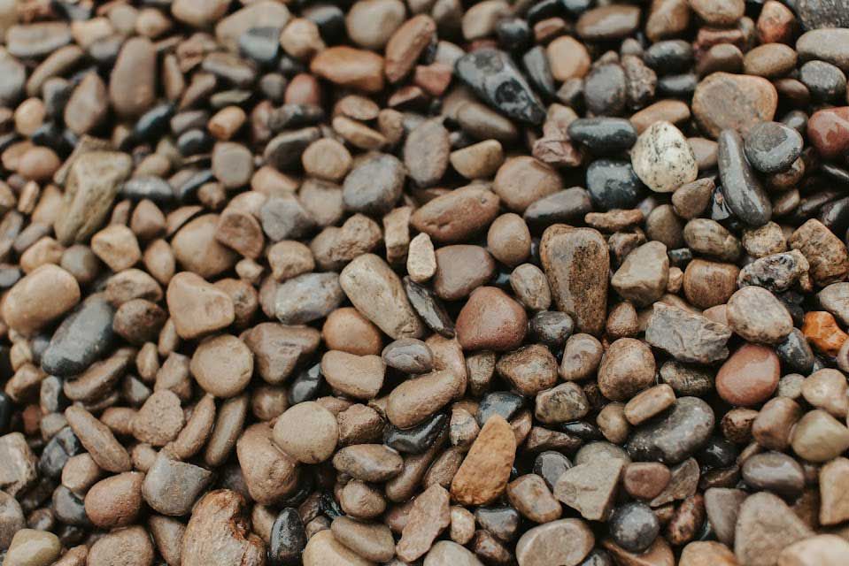 Pile of smooth, wet river rocks in varying shades of brown, gray, and black.