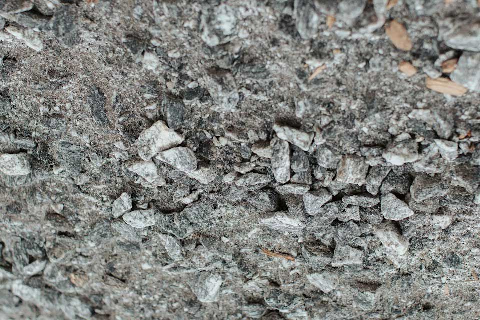 Close-up of a rough gray surface with small, irregularly shaped gray stones and dust.
