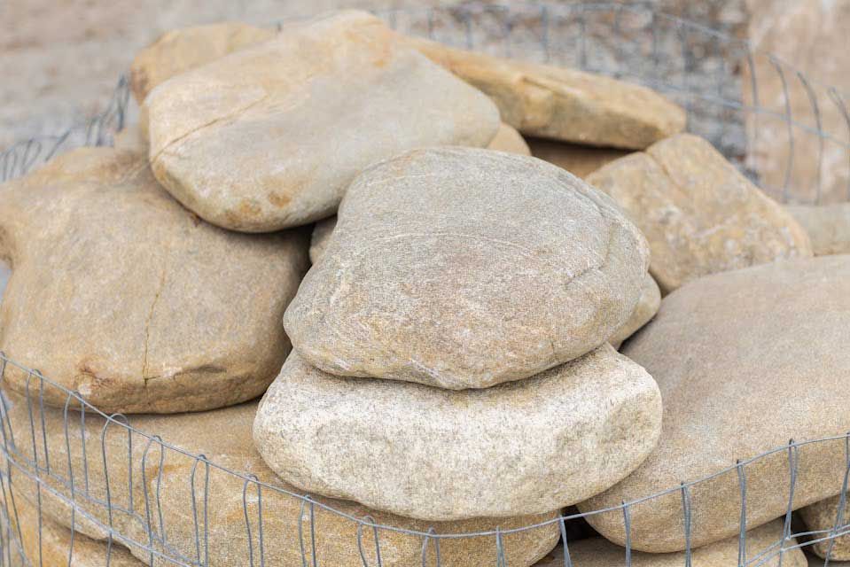 Large beige landscaping stones stacked in a wire cage.
