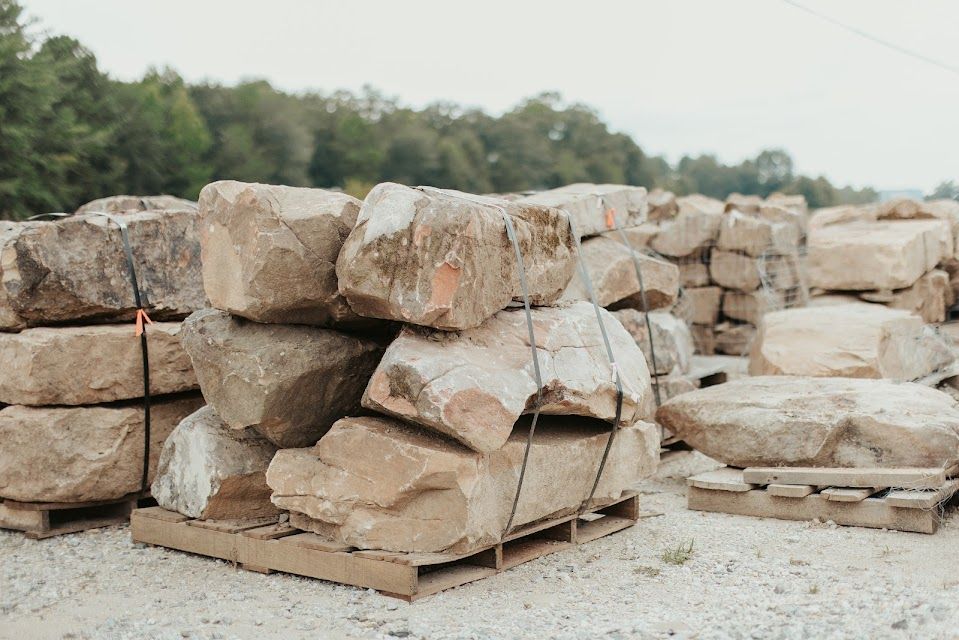 Stacks of large, beige rocks on wooden pallets, outdoors.