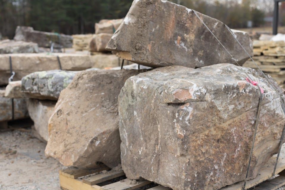 Pile of large, rough, brown and gray rocks on a wooden pallet, likely for landscaping.