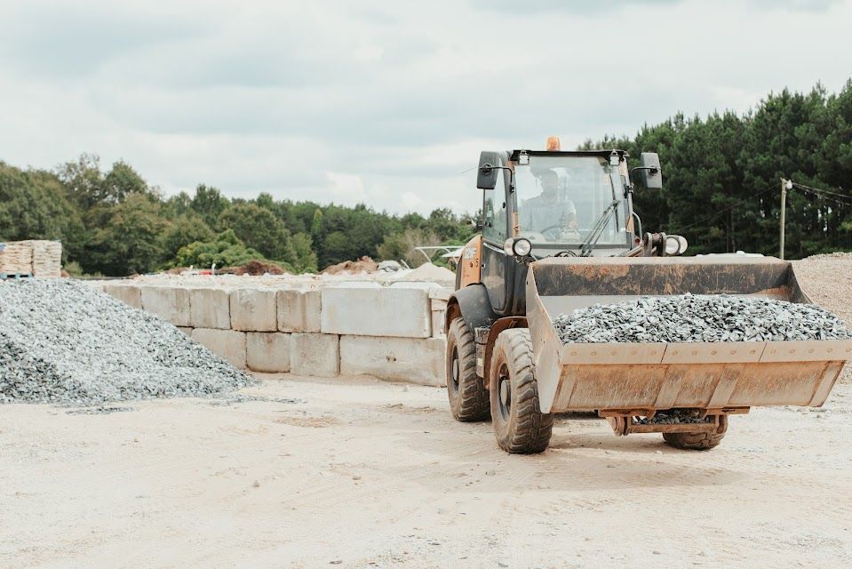 Yellow loader with a full bucket of rocks on a construction site.