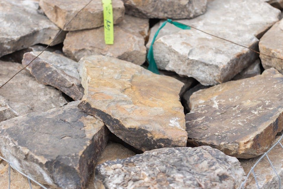 Pile of rough-hewn tan and gray rocks. A green tag is visible.