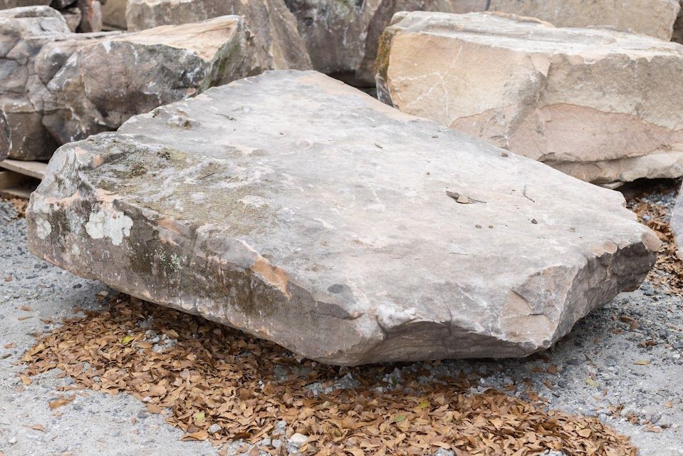 Large gray and tan rock on a bed of small brown stones; possibly in a landscaping setting.