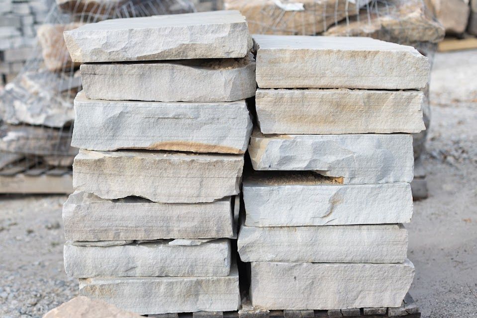 Stack of rectangular, light-colored stone pavers; outdoor setting.