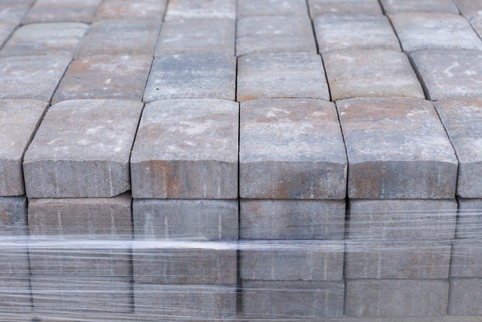 Stack of gray and brown paving stones wrapped in clear plastic.