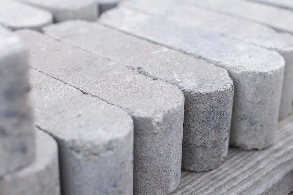 Close-up of a stack of gray concrete paving stones with rounded edges.