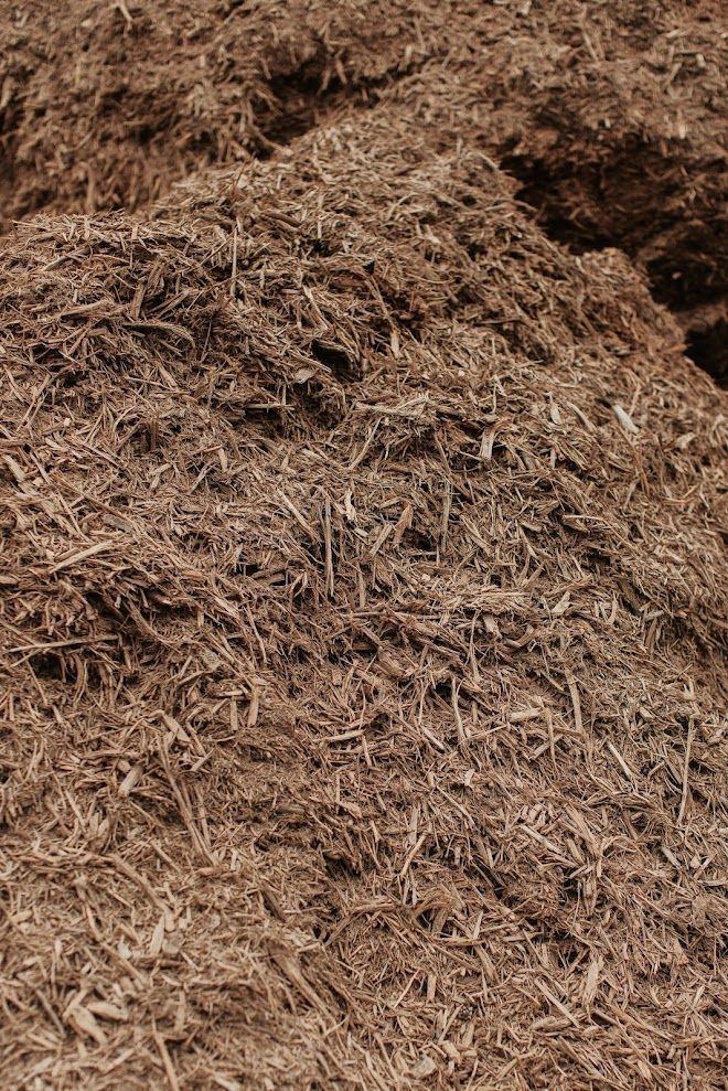 Pile of brown mulch, consisting of shredded wood pieces, for gardening use.