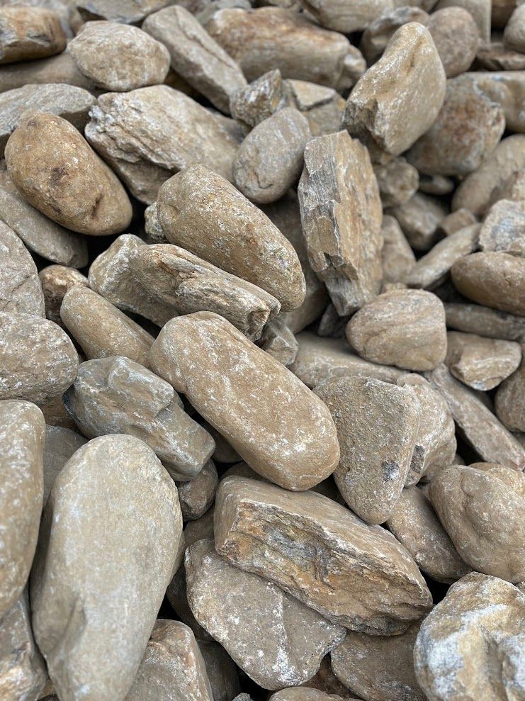 Pile of tan and beige river rocks, varying in size and shape.