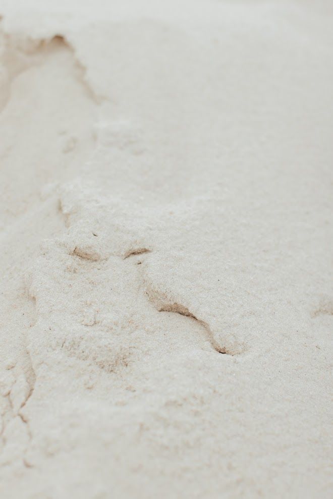 Close-up of white sand with a textured, uneven surface; small indentations.