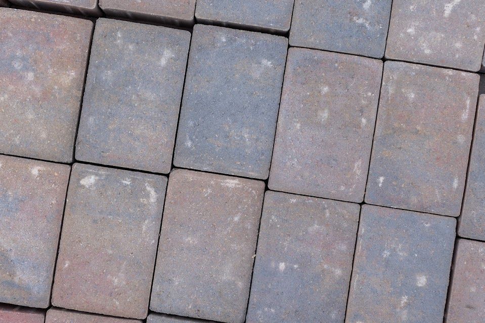 Close-up of rectangular paving stones in various shades of grey, blue and reddish-brown.
