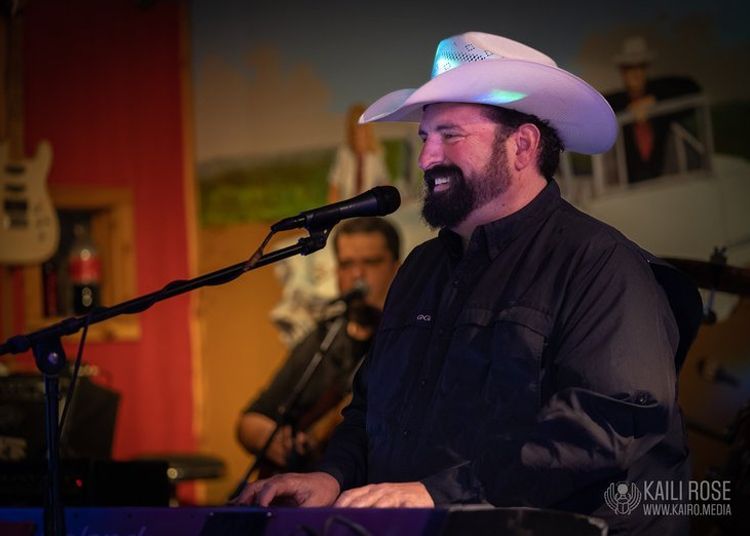 A man in a cowboy hat is singing into a microphone