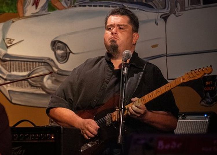 A man is singing into a microphone while playing a guitar