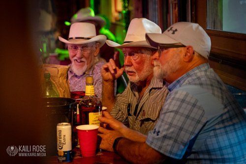 Three men wearing cowboy hats are sitting at a table in a bar.