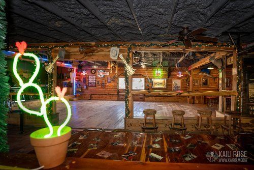A neon cactus in a pot is sitting on a table in a room.