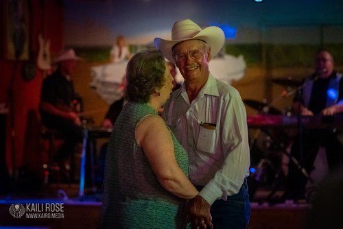 A man in a cowboy hat is dancing with a woman in a green dress.