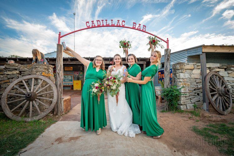 A bride and her bridesmaids are posing for a picture in front of a sign.