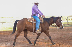 A man is riding a brown horse in a dirt field.