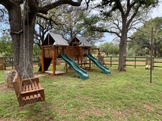 A playground with a swing hanging from a tree and a slide.