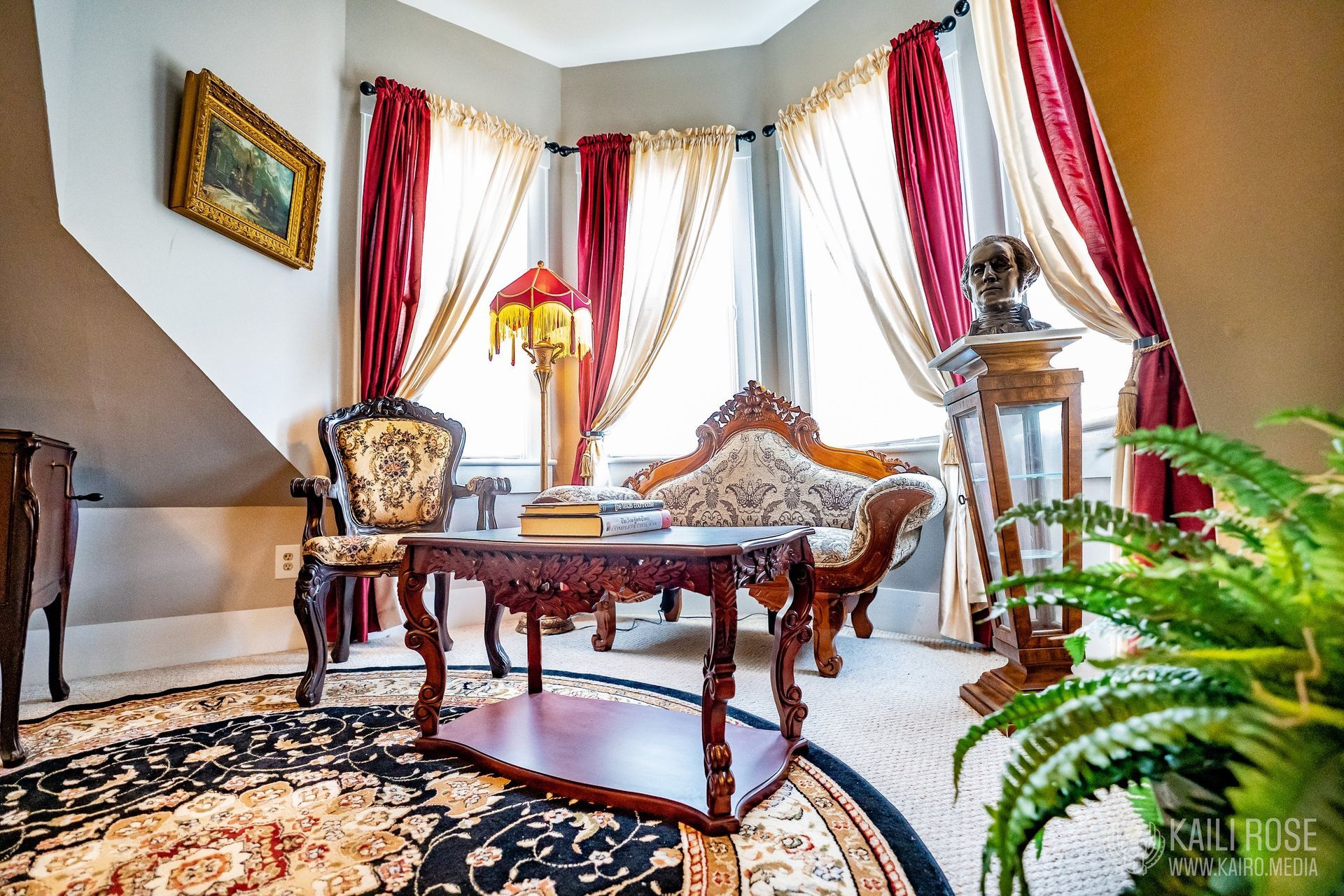 A living room with a couch, table, chairs and curtains.