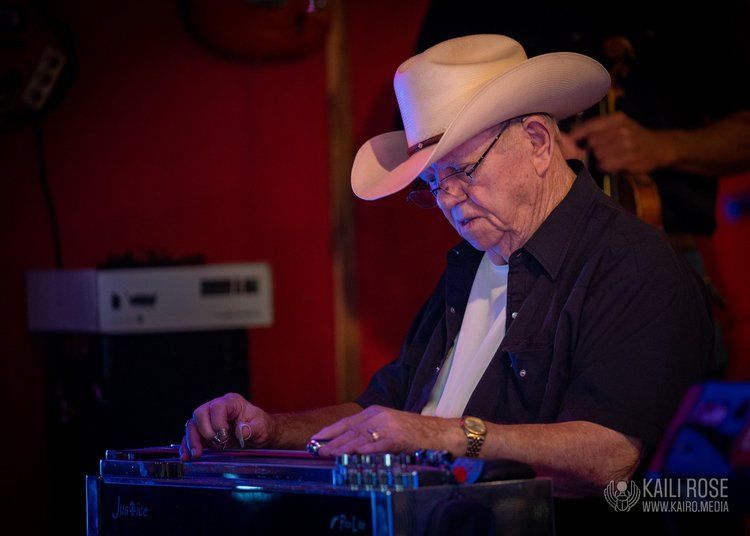 A man in a cowboy hat is playing a guitar on a stage.