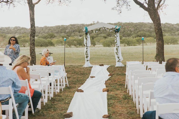 A group of people are sitting at a wedding ceremony in a field.