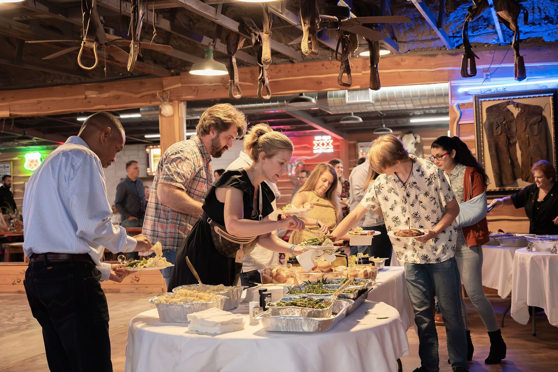 A group of people are standing around a table eating food.