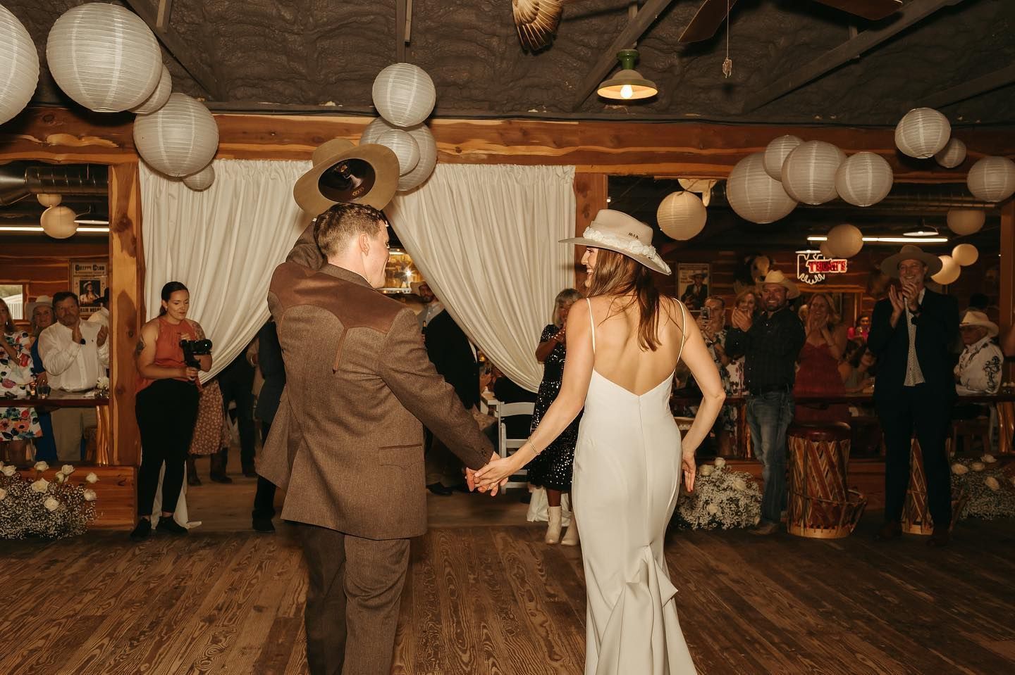 A bride and groom are holding hands while dancing at their wedding reception.