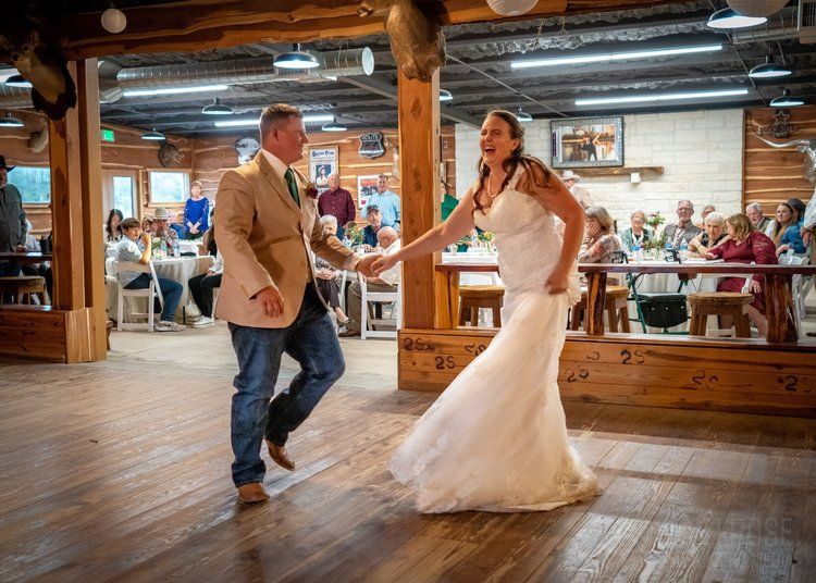 A bride and groom are dancing on a wooden floor at their wedding reception.