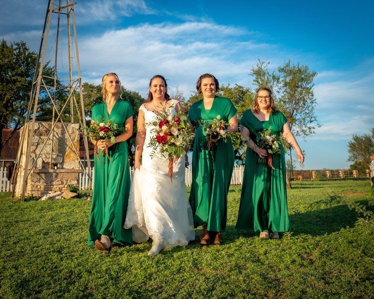 A bride and her bridesmaids are posing for a picture in a field.