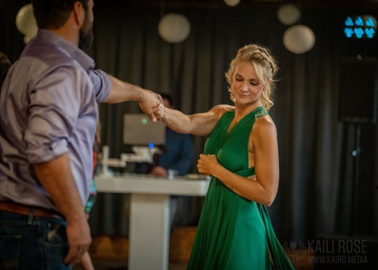 A woman in a green dress is dancing with a man in a purple shirt.
