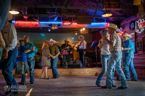 A group of people are dancing in front of a band in a bar.