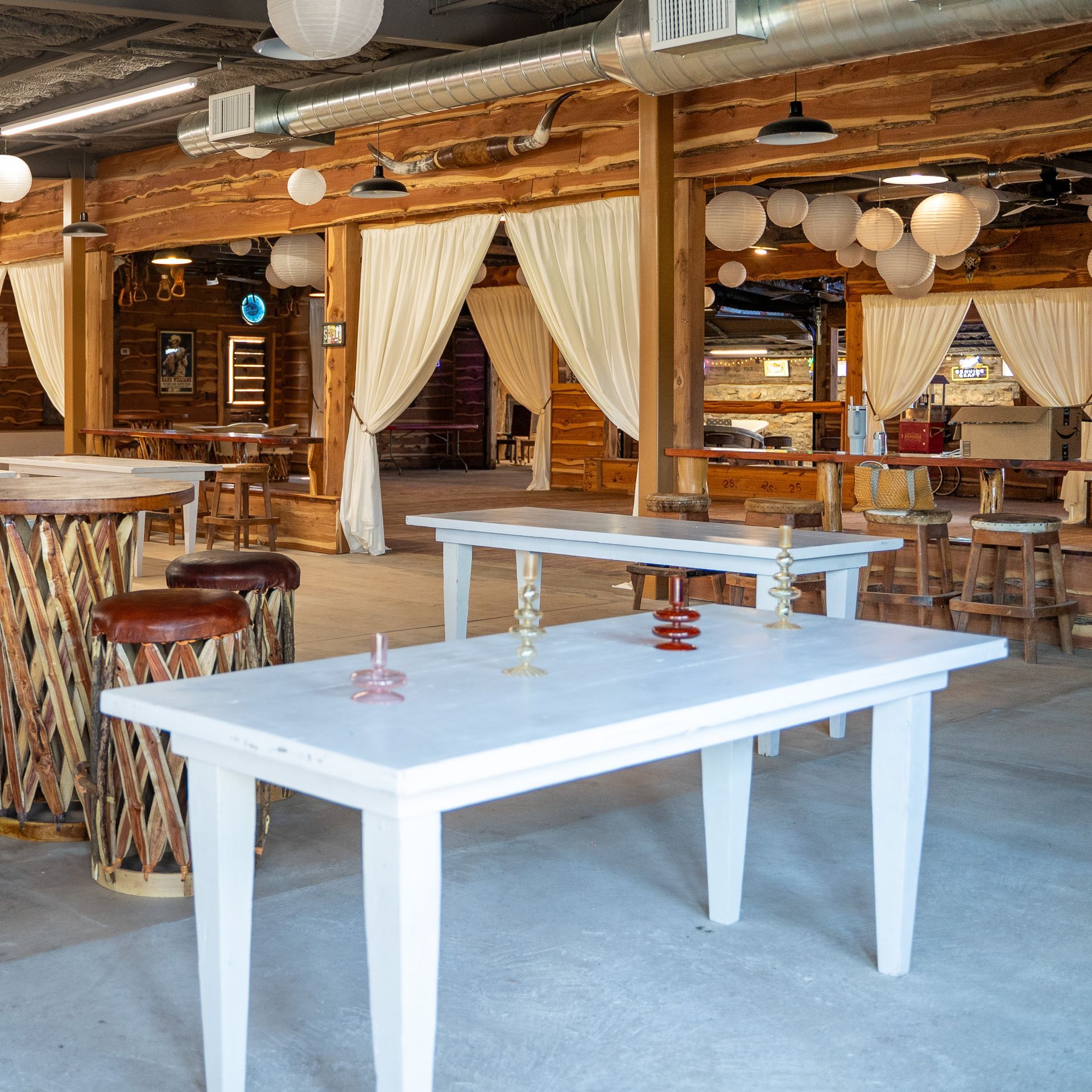 A large room with white tables and stools