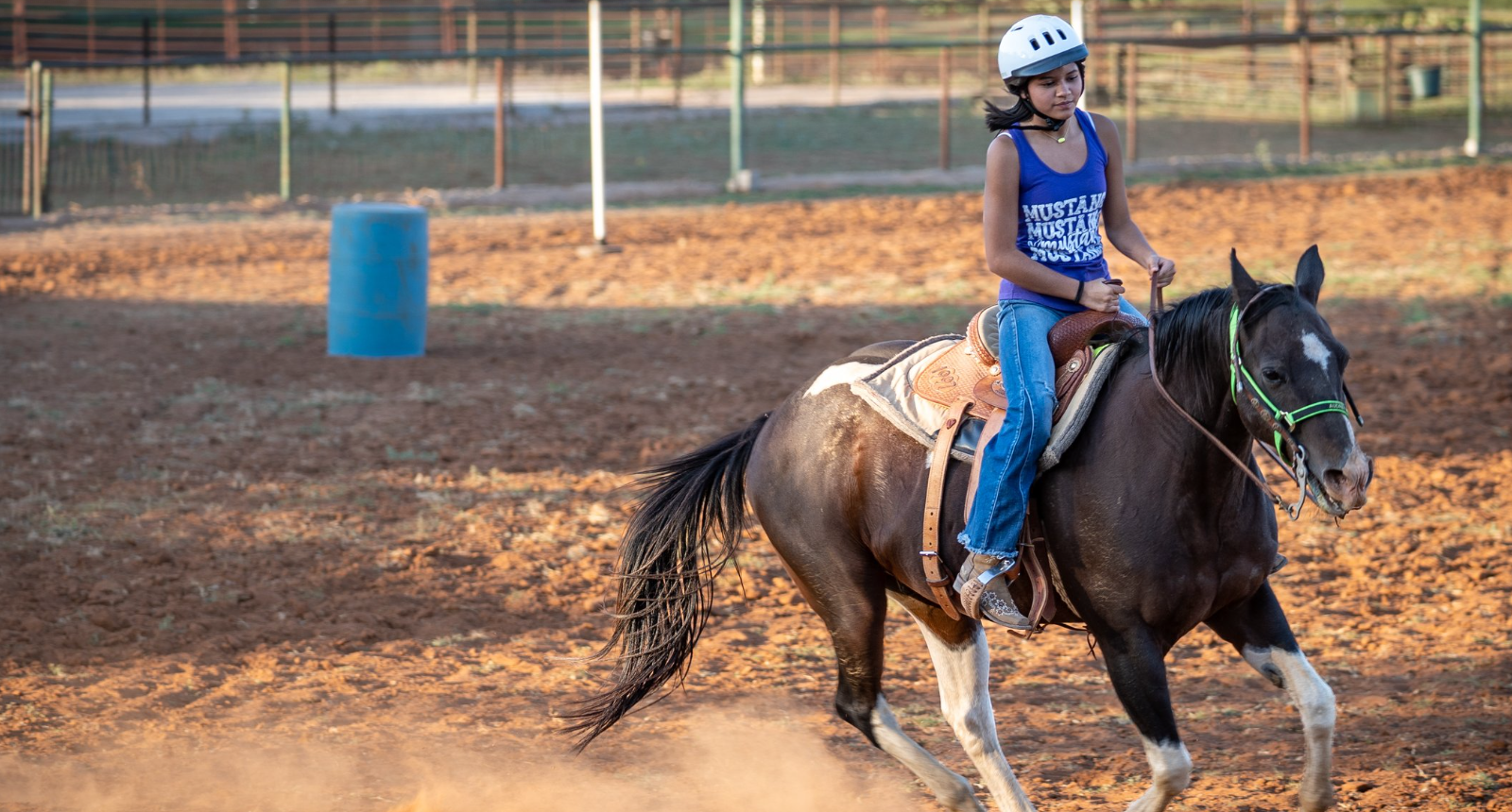 A woman is riding a horse in a dirt field.