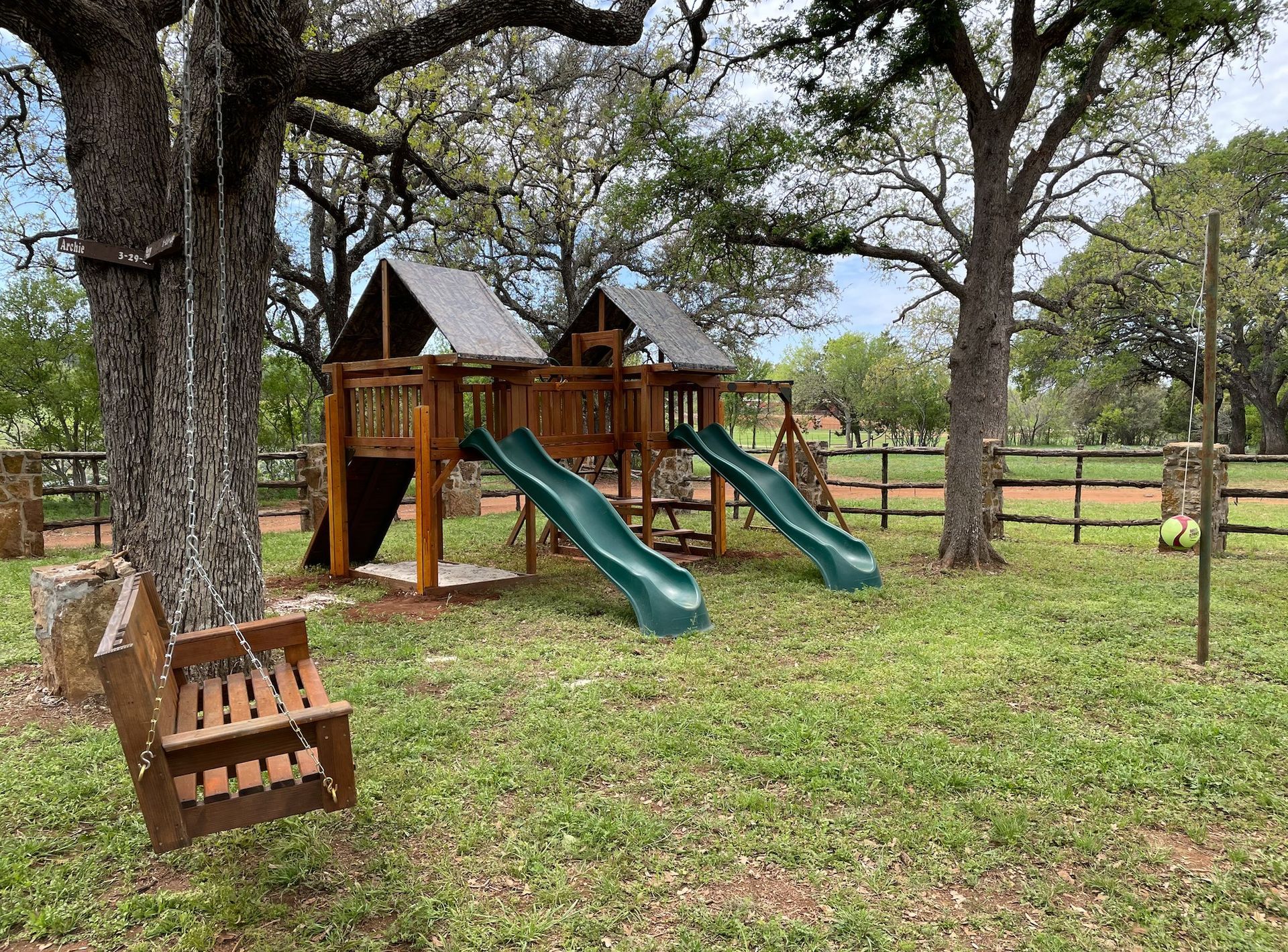 A playground with a swing and a slide in a grassy field.