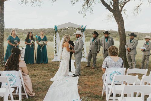 A bride and groom are getting married in a field with their wedding party.