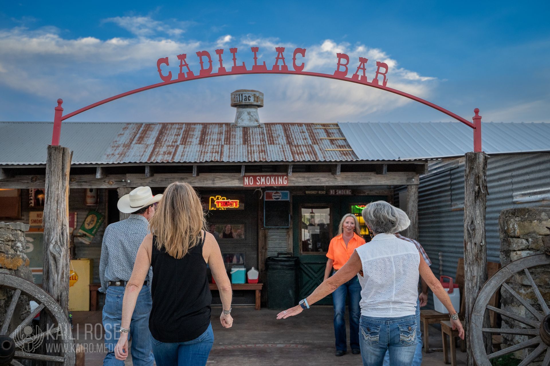 A group of people are standing in front of a cadillac bar.