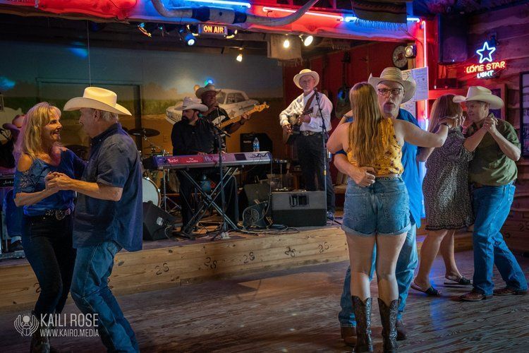 A group of people are dancing in a room in front of a band.