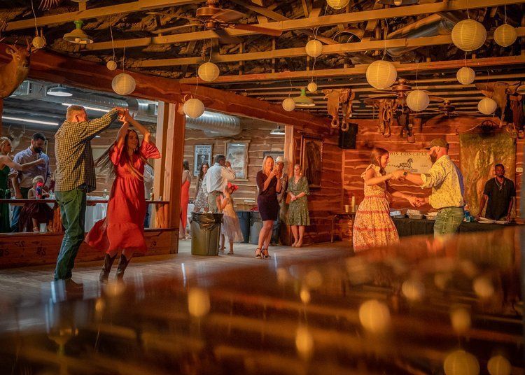 A group of people are dancing in a room with lanterns on the ceiling.