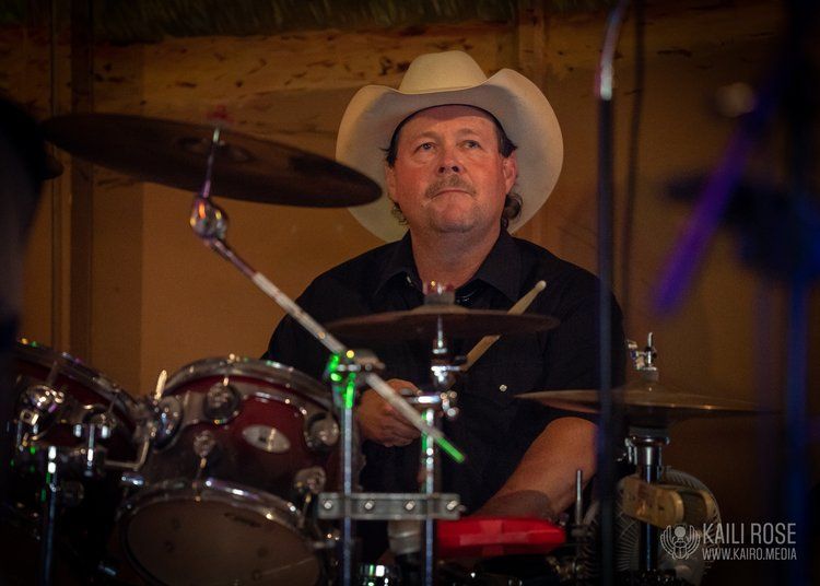 A man in a cowboy hat is playing drums