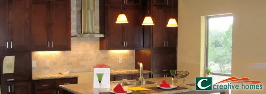 Kitchen with dark wood cabinets, a light-colored countertop and island, pendant lights, and a window.